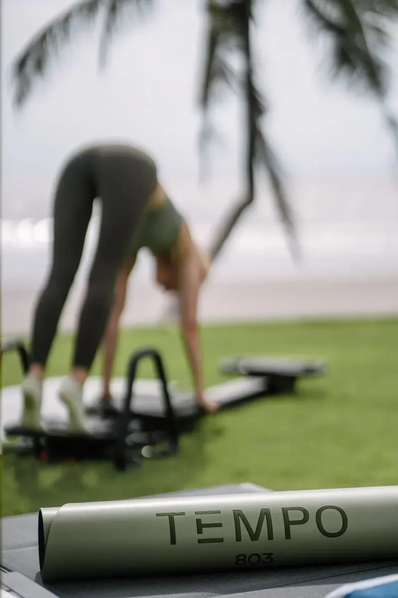 Workout on branded Tempo mat beneath palm trees