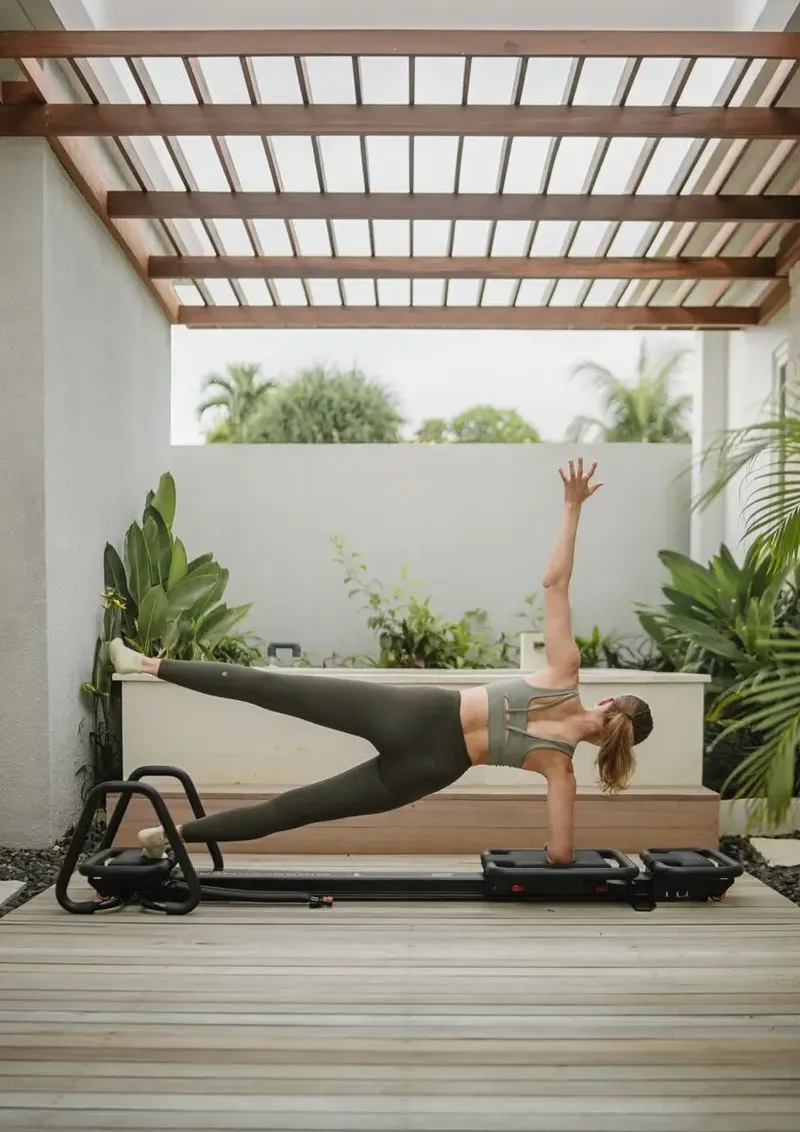 Side plank on a Megaformer under a tropical pergola